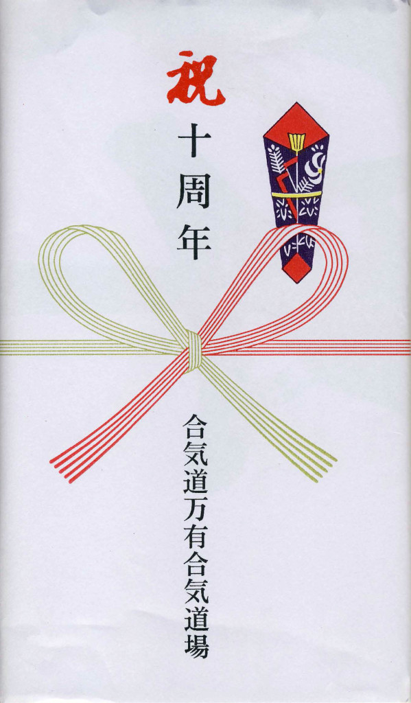 Il tenugui viene regalato piegato e incartato con questa carta regalo tradizionale giapponese. Dall'alto verso il basso: "10° anniversario". Sotto il fiocco: "Aikido Banyuaiki Dojo".